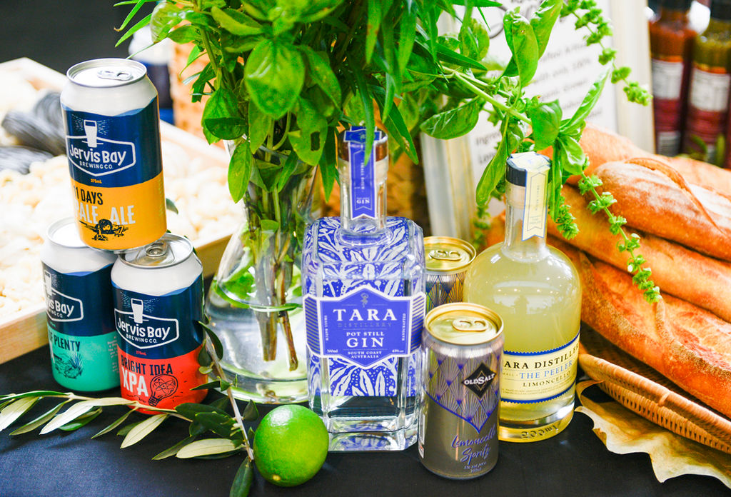 Local beverages from Jervis Bay Brewing Co. and Tara Distillery showcased with fresh herbs and bread.