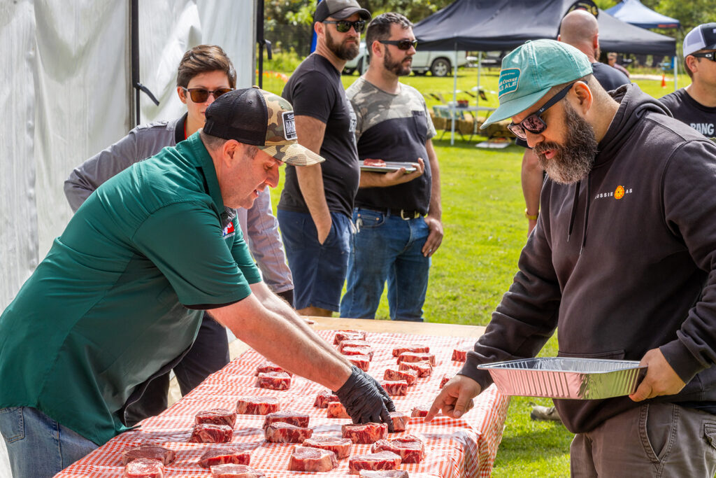 Festival-goers selecting premium cuts of raw steak from a vendor at the sunny Kangaroo Valley Craft Beer and BBQ Festival.