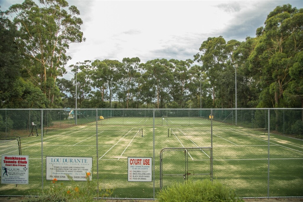 Players enjoying a morning match at the Huskisson Tennis Courts surrounded by native green bushland in Jervis Bay, NSW.