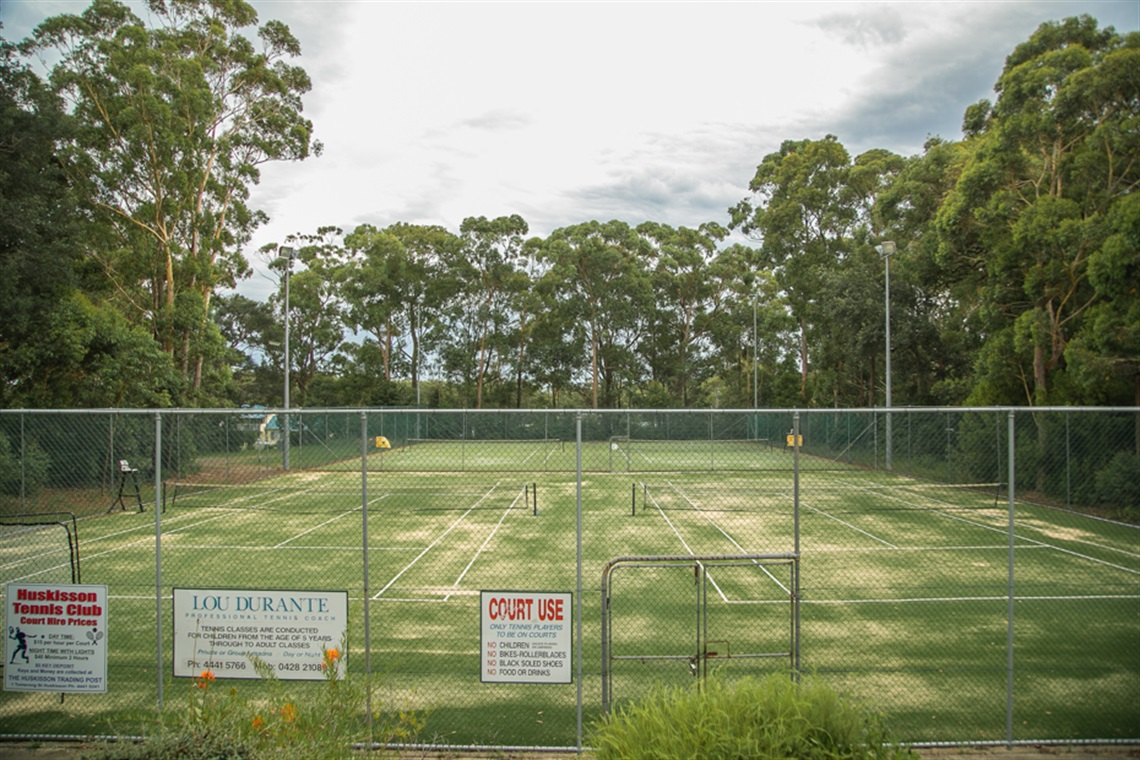 Players enjoying a morning match at the Huskisson Tennis Courts surrounded by native green bushland in Jervis Bay, NSW.
