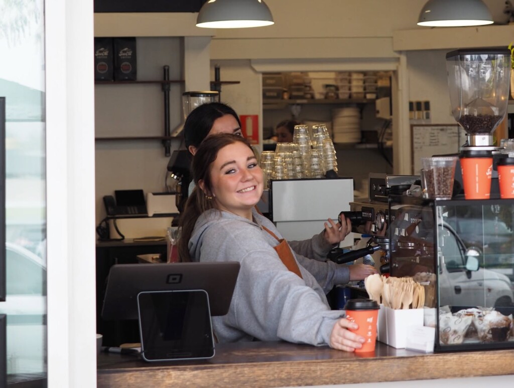 Friendly barista preparing takeaway coffee at 5 Little Pigs café in Huskisson, NSW.