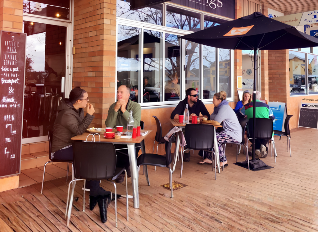 Outdoor dining area at 5 Little Pigs café in Huskisson, NSW, with guests enjoying breakfast and coffee.