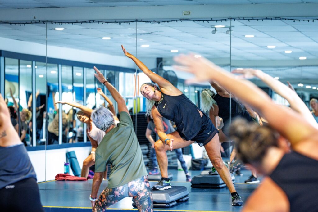 Adults participating in a group fitness class inside a gym