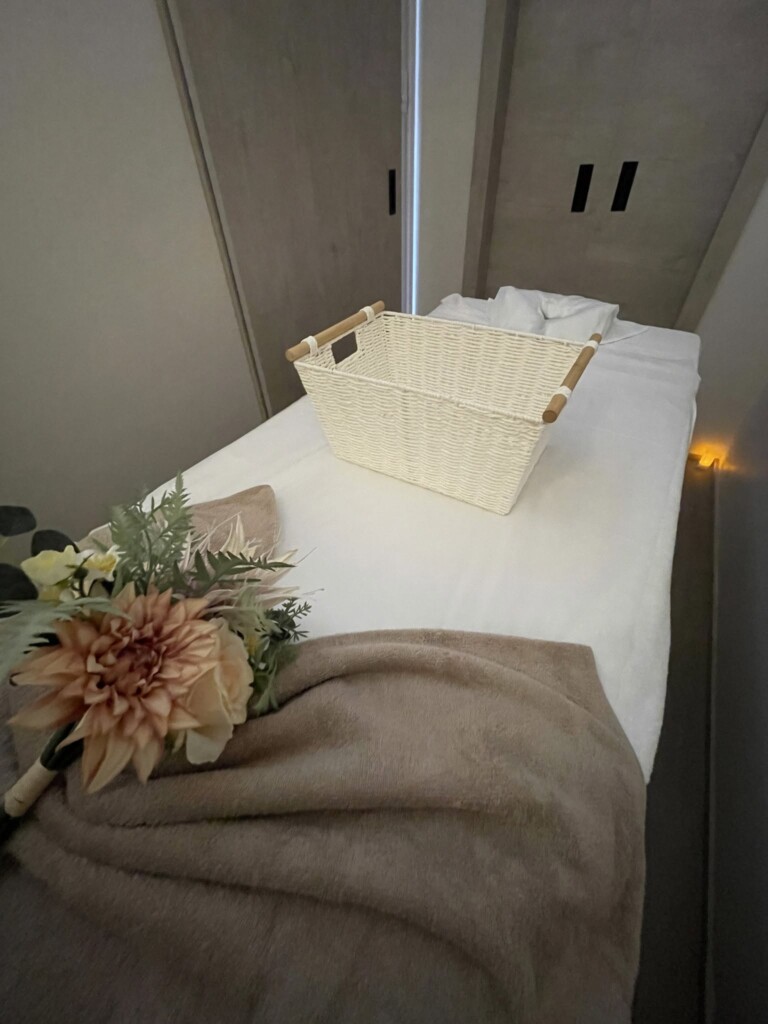 Thai massage treatment room with fresh flowers, towels and a comfortable massage bed