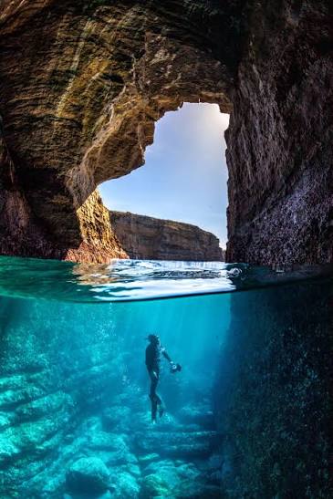 Swimmer exploring clear blue water inside a coastal cave near Jervis Bay