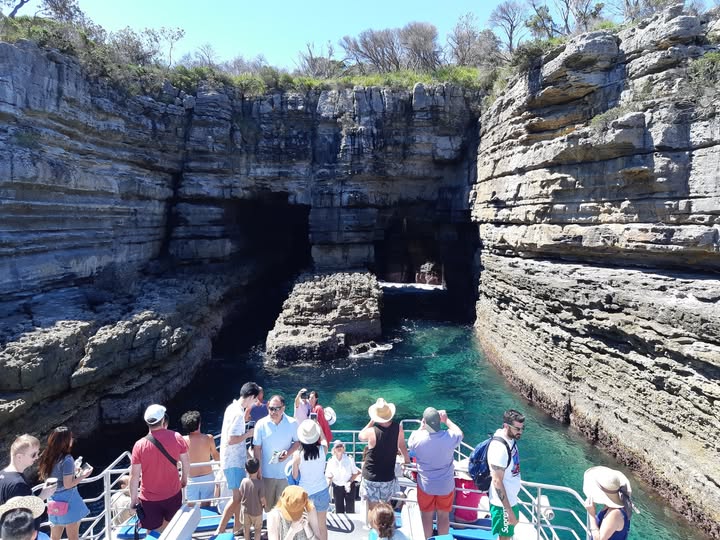 Visitors exploring a dramatic coastal cave by boat in Jervis Bay