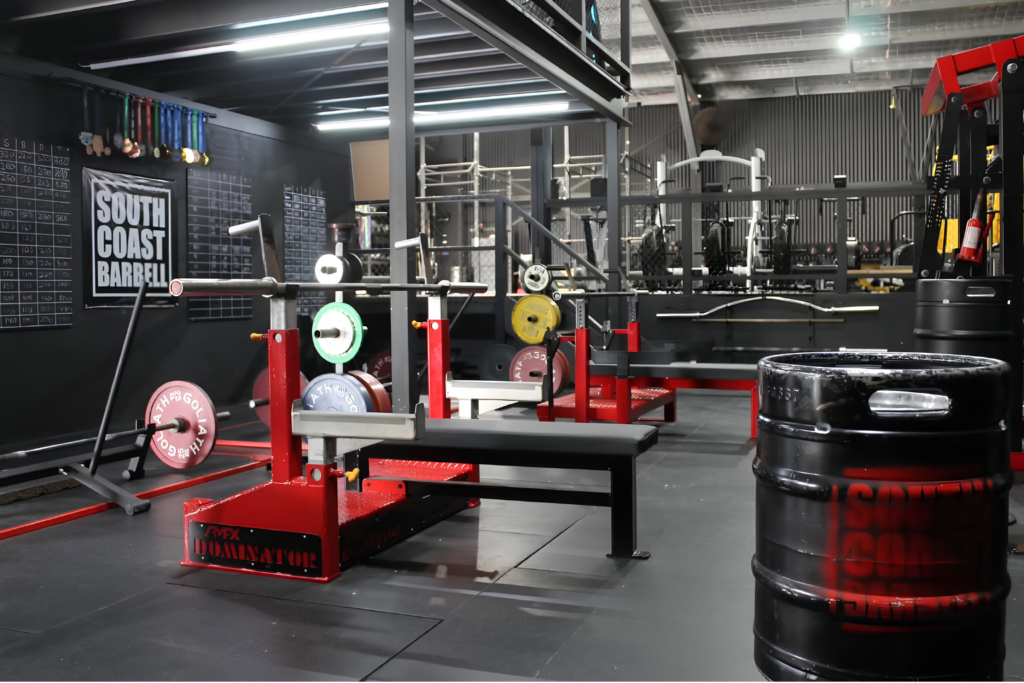 Gym trainer supervising a woman using strength training equipment at South Coast Barbell in Huskisson.