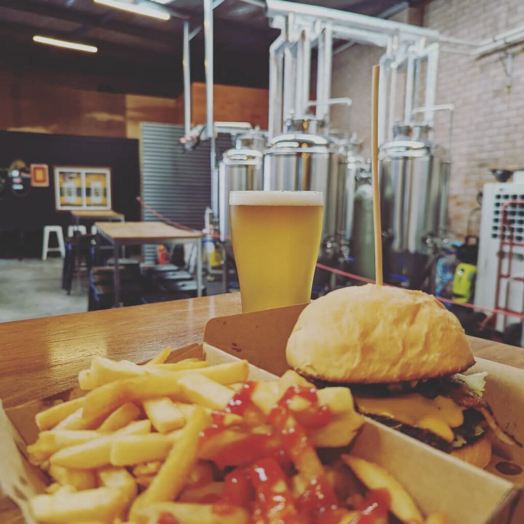 Groups of visitors enjoying food and drinks at communal tables inside South Yeast Brewing's busy taproom.